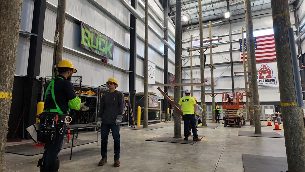 Crew members in hi-vis and hard hats working among the poles inside the indoor training facility
